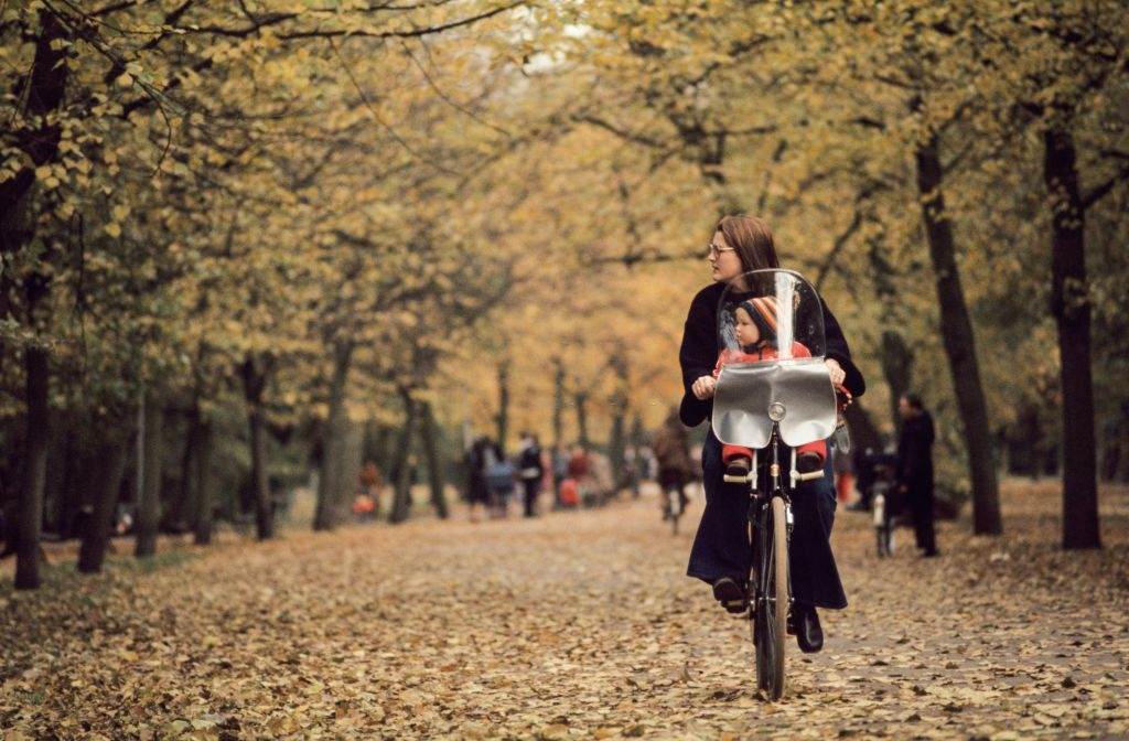 A mother with her child cycling through Autumn leaves in Vondel Park in Amsterdam, September 1976.
