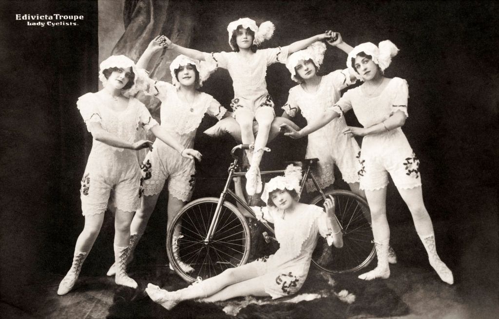 A vintage postcard featuring a troupe of performing lady cyclists posing in their costumes, Amsterdam, 1920s.