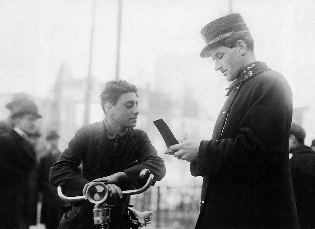 A policeman writing out a ticket for a cyclist in Amsterdam, 1924.