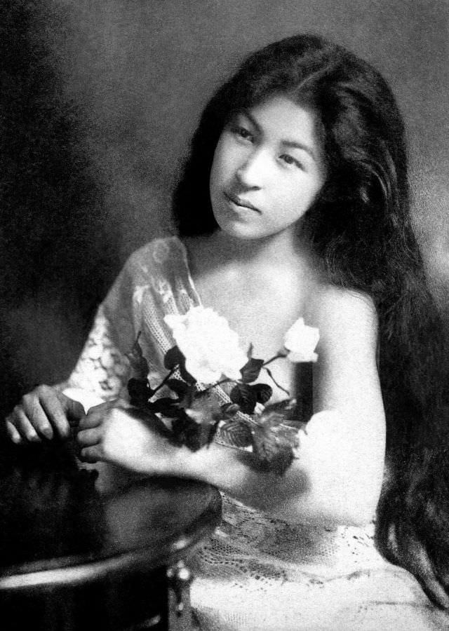 A geisha with her hair down, holding white roses