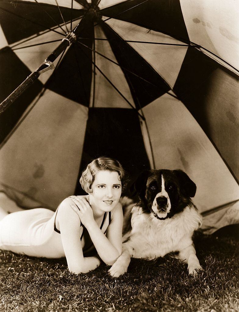 Jean Arthur sitting under an umbrella with 'Major', her St Bernard's dog, 1931.