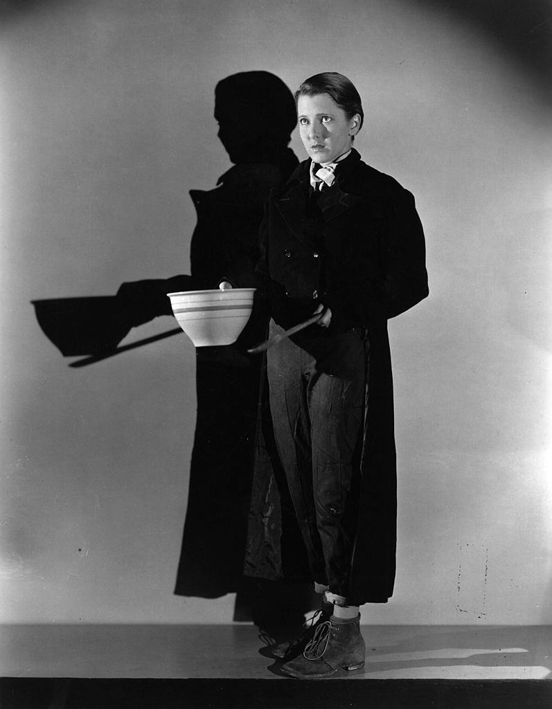 Jean Arthur doing an impression of Oliver Twist, holding out a bowl and asking for more, 1933.