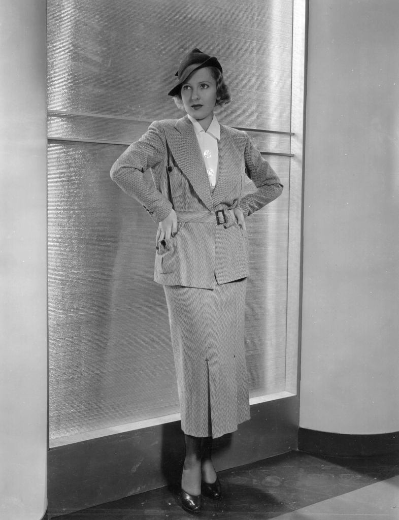 Jean Arthur wearing a sensible and attractive suit of mustard and tan, with patch pockets and kick pleats in the skirt front, 1935.