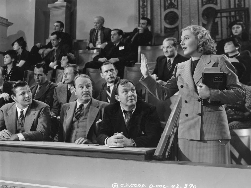 Jean Arthur swearing in at court, in the presence of actors Thomas Mitchell and Jack Carson in a scene from the political satire 'Mr Smith Goes to Washington', 1939.