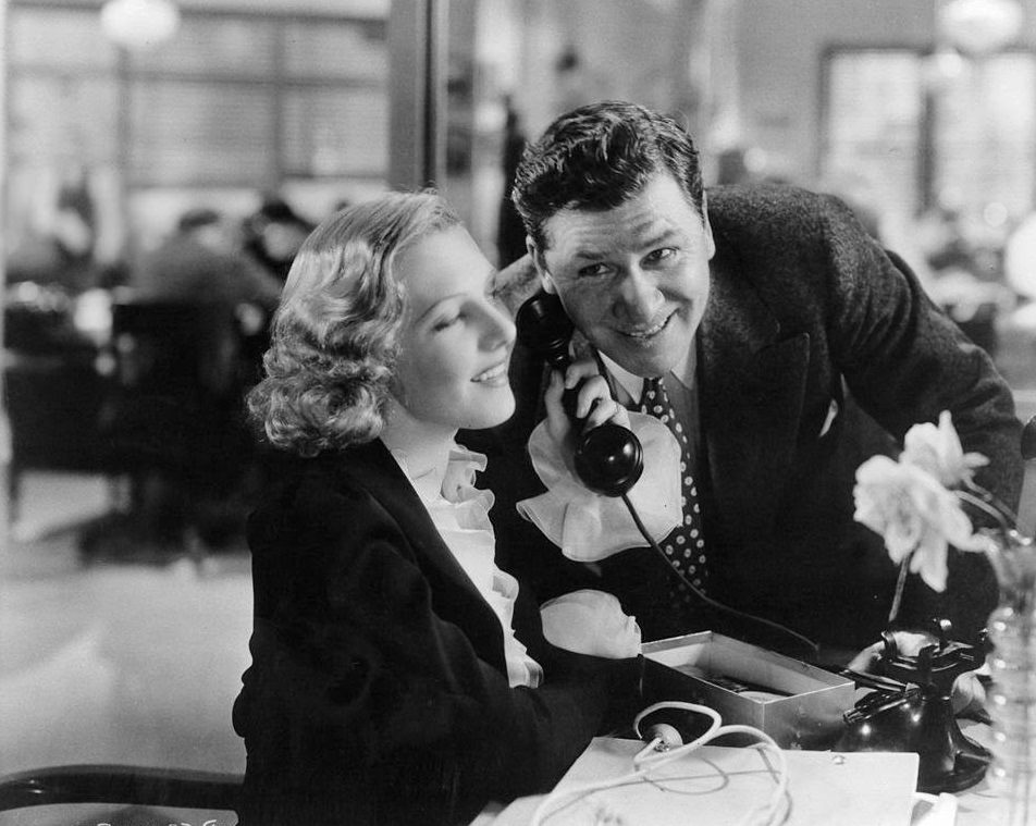 Jean Arthur and Gary Cooper listen to a phone call in a scene from the film 'Mr. Deeds Goes To Town', 1936.