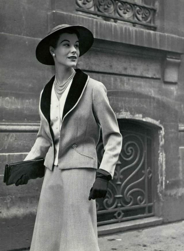 Myrtle Crawford in gray wool suit with black velvet shawl collar worn over white piqué vest, 1953