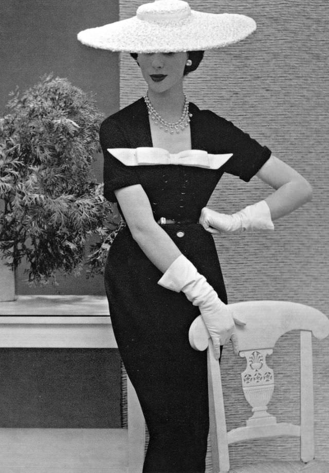 Myrtle Crawford in navy blue dress with white pique bow and white straw hat exemplifies the Nina Ricci style, 1953