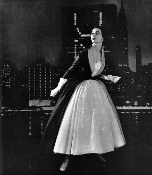Myrtle Crawford in white organza dress embroidered with flowers and rhinestones, worn with black organza coat lined in beige organza, by Givenchy, 1953