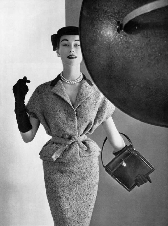 Myrtle Crawford in blue tweed two-piece with navy toile collar, the cut of the armholes evokes a chasuble, by Givenchy, 1954