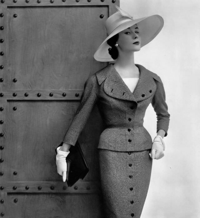 Myrtle Crawford in heather gray wool suit, vertical line continues from the buttoned jacket down the skirt, by Jacques Fath, 1954