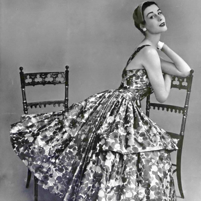 Myrtle Crawford in lovely silk taffeta dress in pink and blue floral print, two straps hold the bodice, the wide skirt is formed by two ruffles in front, by Maggy Rouff, 1954
