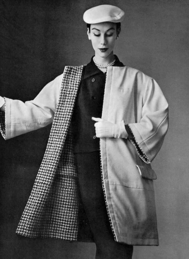 Myrtle Crawford in simple, spare white leather coat, lined in black and white houndstooth, reversible, collarless with no buttons, by Balenciaga, 1954.