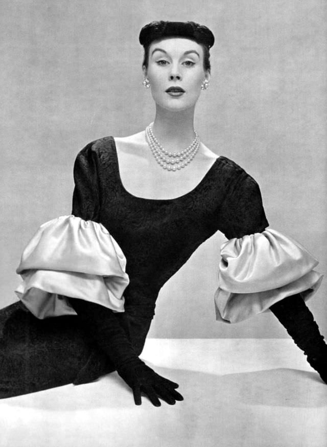 Myrtle Crawford in beautifully black shaped silk dress with flat low neckline, and large blue satin sleeves that give it an original touch, by Balenciaga, 1953
