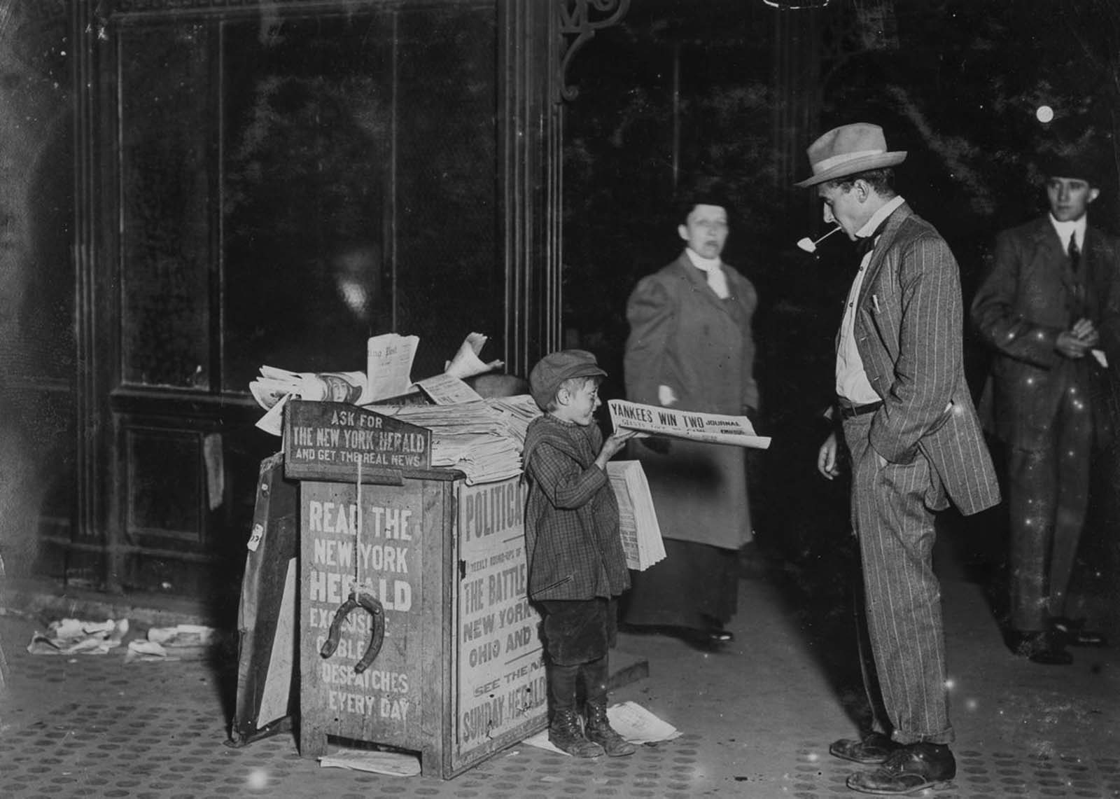 Jerald Schaitberger of 416 West 57th Street, who helps an older boy sell papers until 10 p.m. on Columbus Circle, 1910