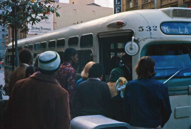 An R-route “old-look” GMC bus picks up passengers on westbound Broadway at 4th Avenue