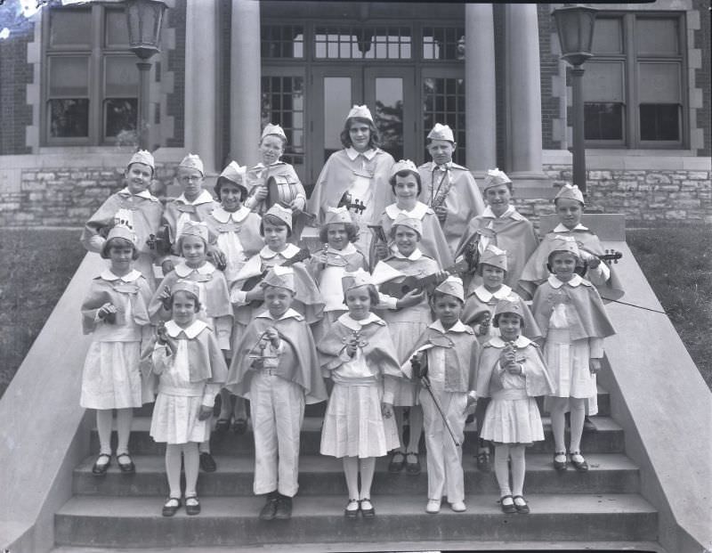 Group of school children posing with instruments on the steps of the Immaculate Conception parish school at 2912 Lafayette, June 1931