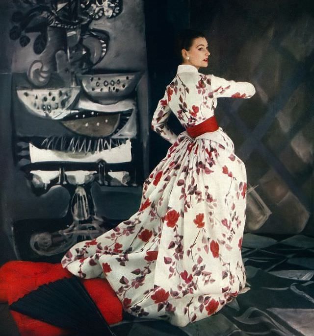 Anne Gunning in beautiful satin-striped silk organdy gown in floral print of reds and dusky leaves worn under its Victorian jacket by Jacques Fath, Vogue, 1954