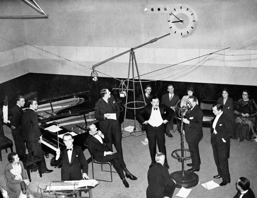 1933: A scene in a 1930s BBC recording studio showing Christopher Stone, wearing a dinner jacket, bidding listeners ‘Good Evening’.