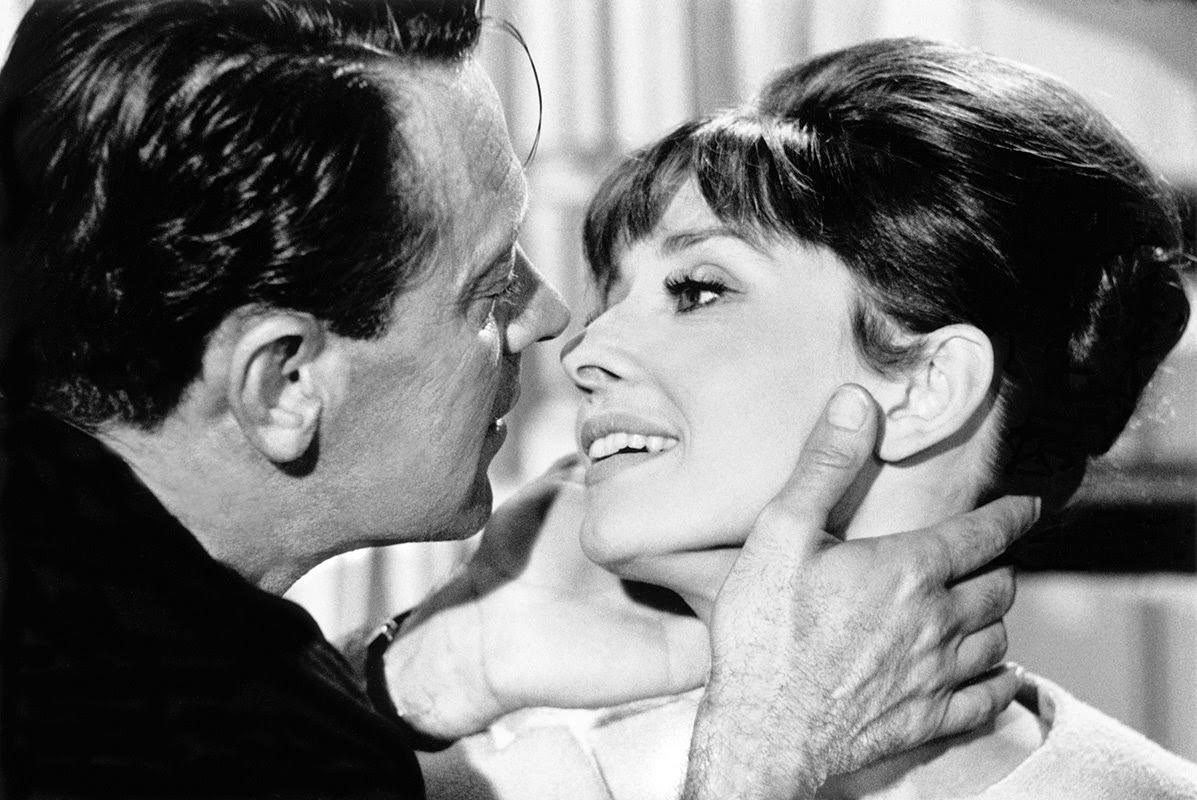 William Holden about to kiss Audrey Hepburn on set of "Paris When It Sizzles" at Boulogne Studios in Paris, 1962