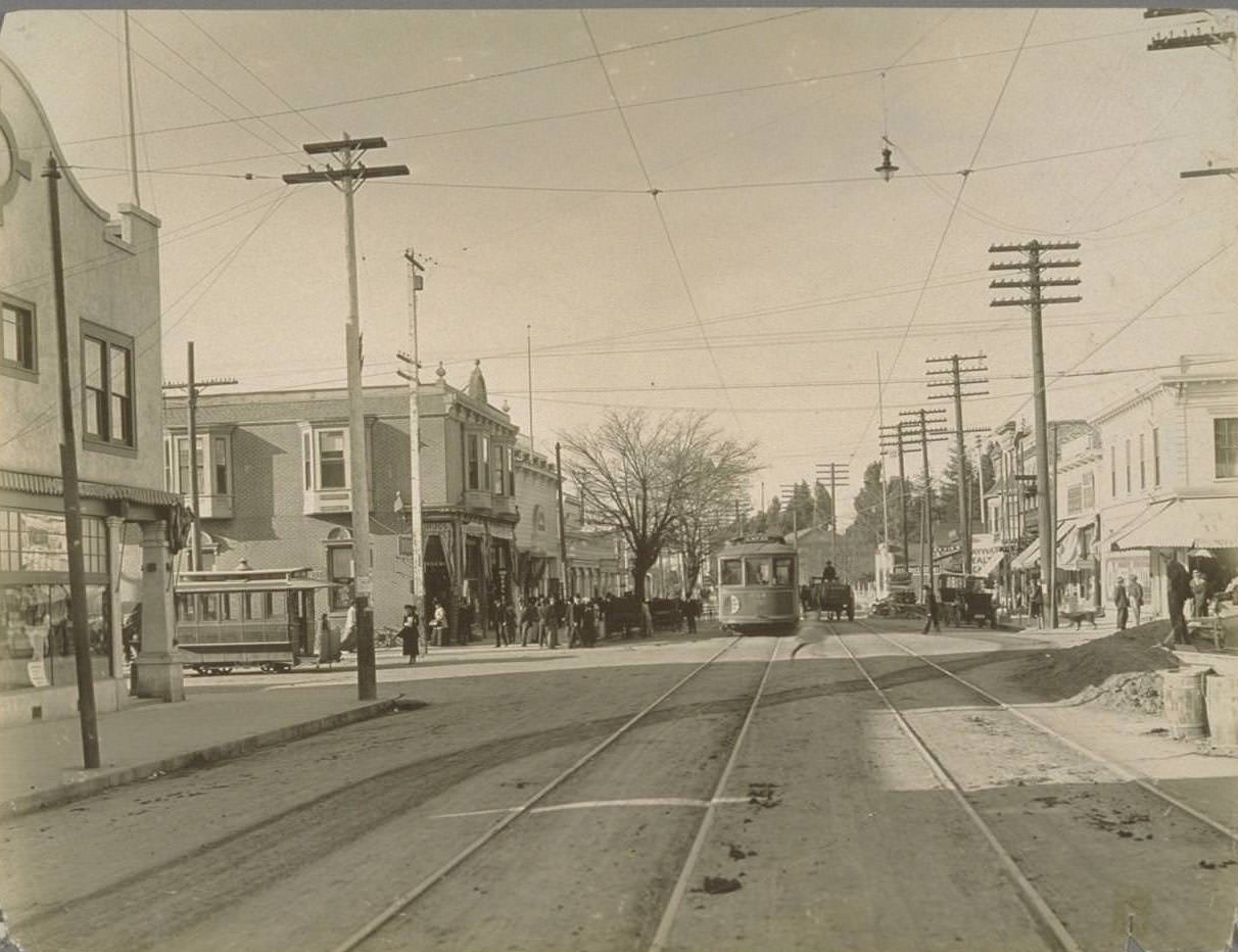 Street scene, with electric trolley cars, horse buggies, and automobiles, 1920s.