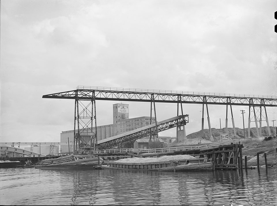 Oyster shell barges at unloading dock of cement plant. Port of Houston, Texas