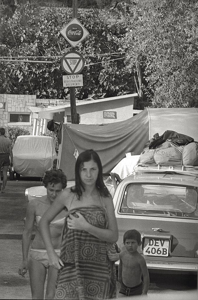 Some campers wearing swimsuit and pareo leaving the camping behind them, Italy, 1960s.