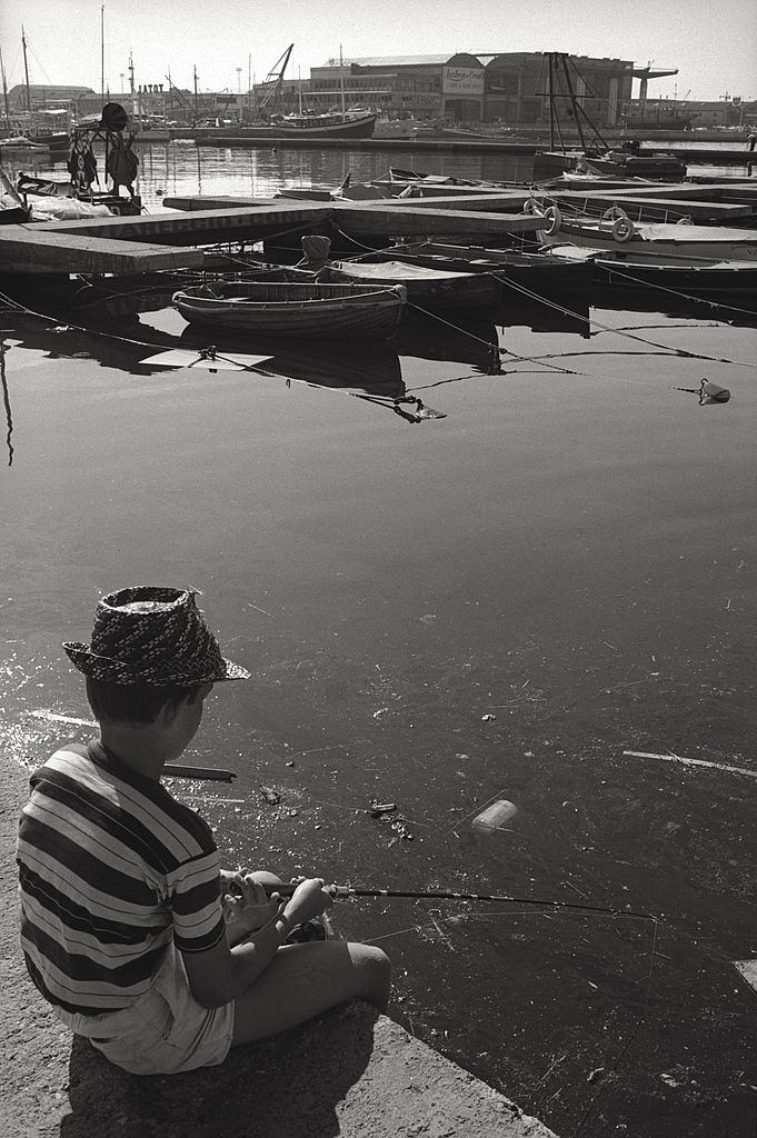 A child fishing in the polluted water of the Viareggio harbour, 1960.