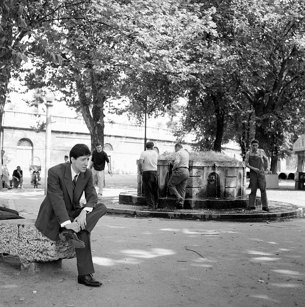 Italian singer-songwriter and actor Giorgio Gaber (Giorgio Gaberscik) sitting in a square. Milan, 1960s.