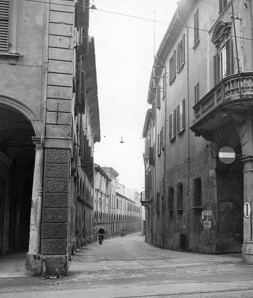 A man riding a bicycle along a street of Bologna., 1960s.