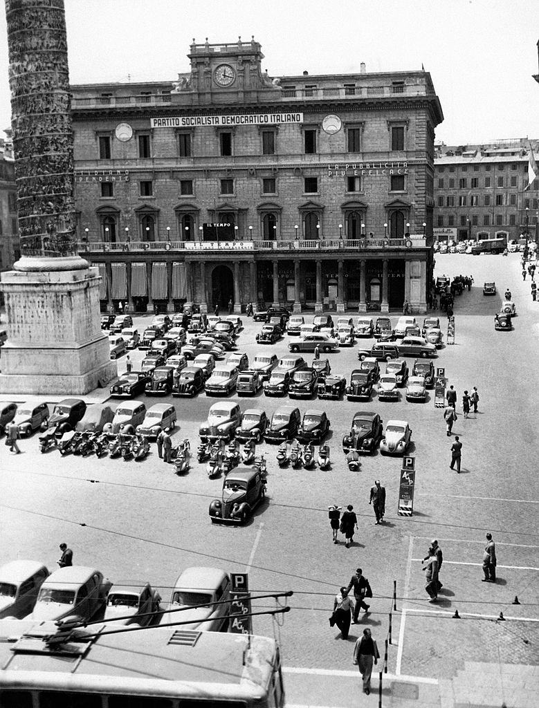 Many cars are parked in front of Palazzo Wedekind in piazza Colonna in Rome, 1960s.