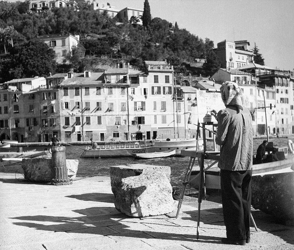 A painter faced backwards paints Portofino's landscape, 1960s.