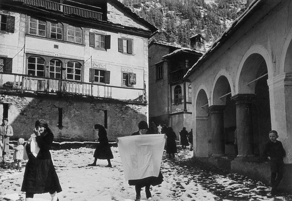 The inhabitants of Carcoforo walking in a square of the village, Carcoforo, 1960s.
