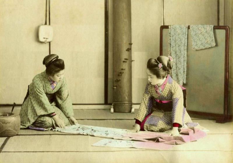 Geishas folding a kimono in old Japan