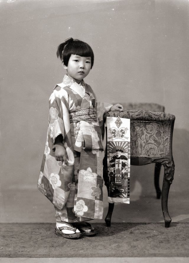 A Japanese girl in a kimono with flowers and checkered pattern. She is also holding Chitose Ame (Thousand Year Candy) for Shichi-Go-San