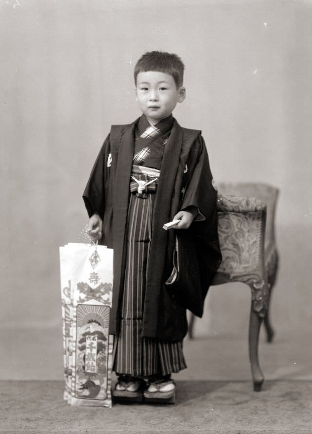 A young Japanese boy in kimono holding traditional Shichi-Go-San candy