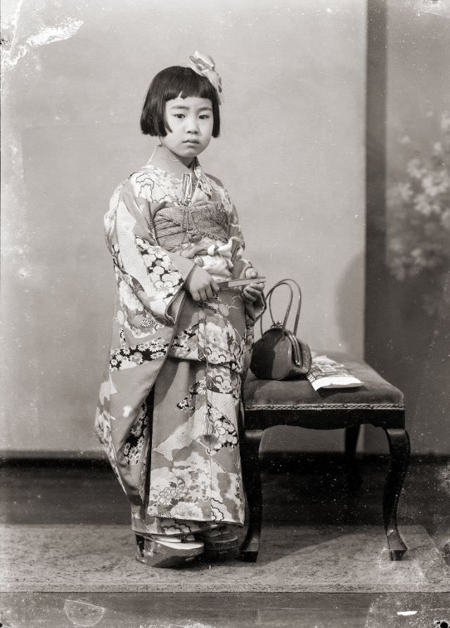 A young Japanese girl in a kimono with a handbag and hair bow