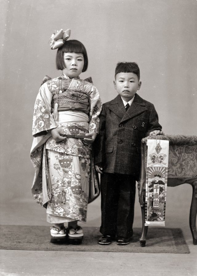 A young Japanese girl in kimono and a young Japanese boy in a suit. The boy is holding Chitose Ame candy, traditional for the Shichi-Go-San festival