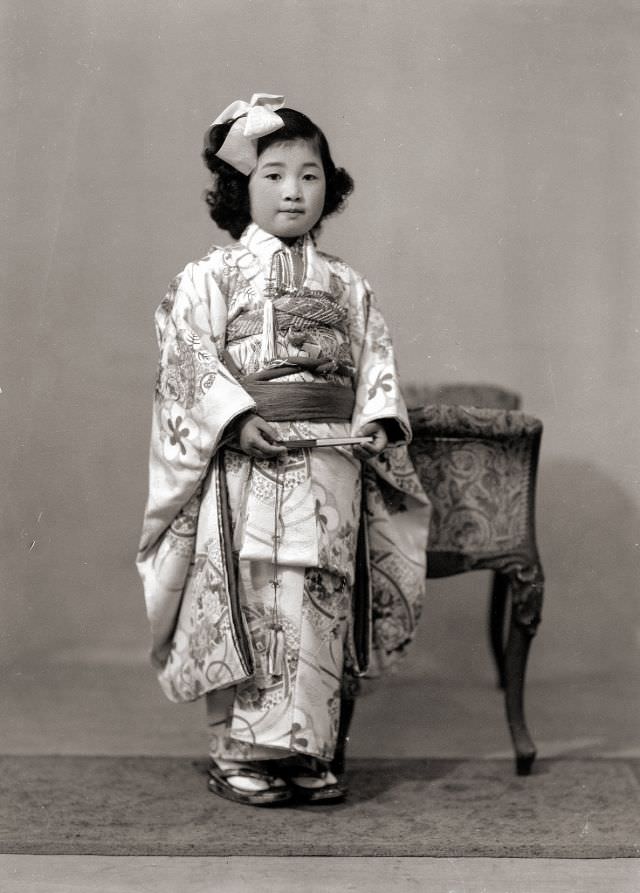 A young Japanese girl in kimono with a hair bow and fan