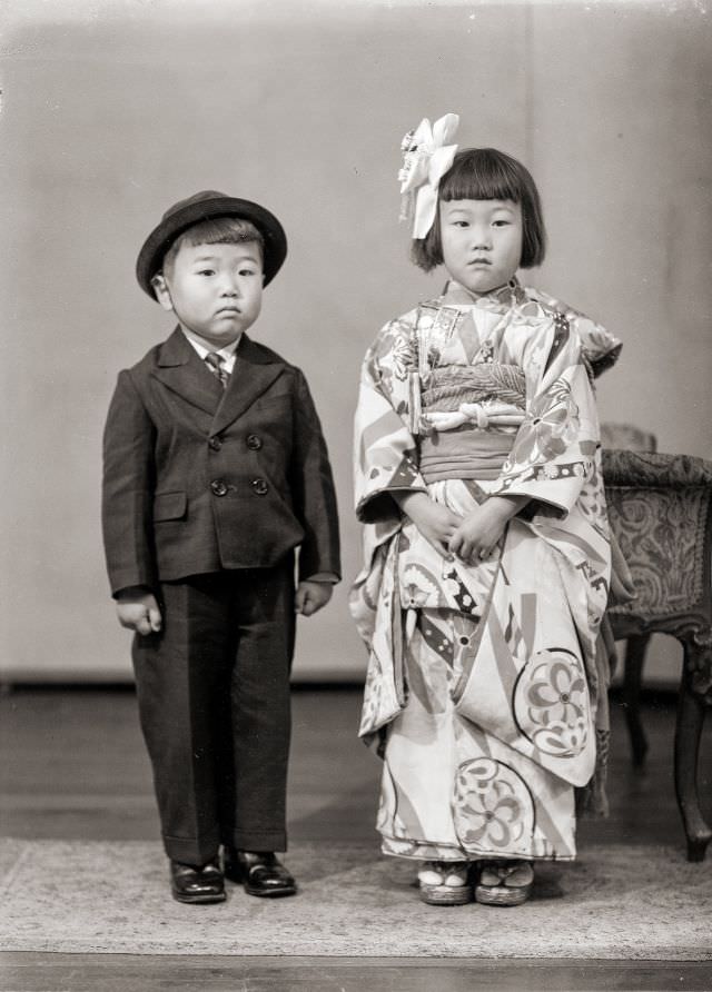 A Japanese boy in a suit with hat and a girl in kimono with hair bow
