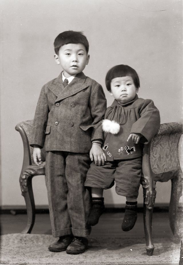 Two Japanese children, one is a suit, posing for a portrait in the old days