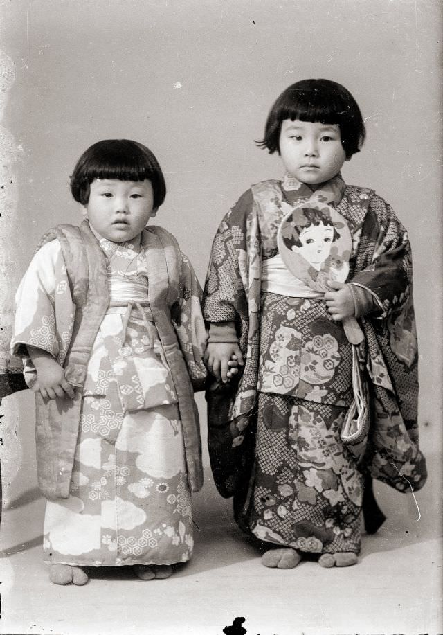 Two young Japanese girls in kimono, one holding what looks like a traditional New Year's hagoita paddle except that it's rounded, not square