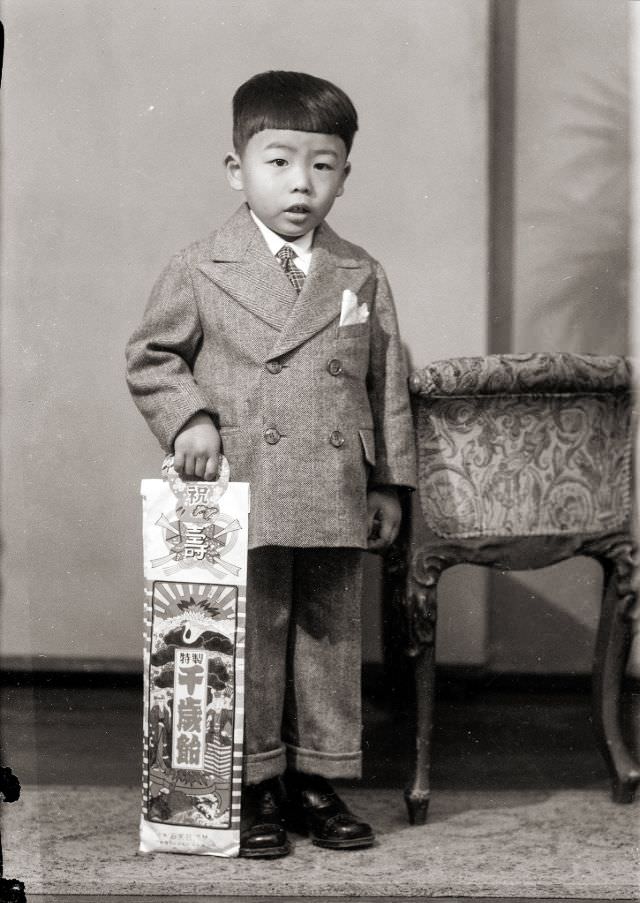 A Japanese boy in a suit with traditional Shichi-Go-San (seven-five-three) candy