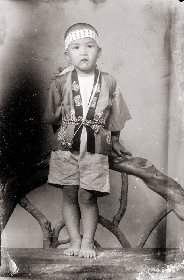 A Japanese boy in a traditional happi coat, a headband, and bells