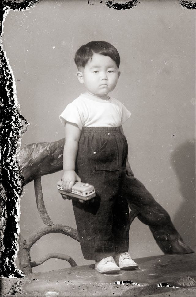 A Japanese boy in very high waist pants and holding a toy train