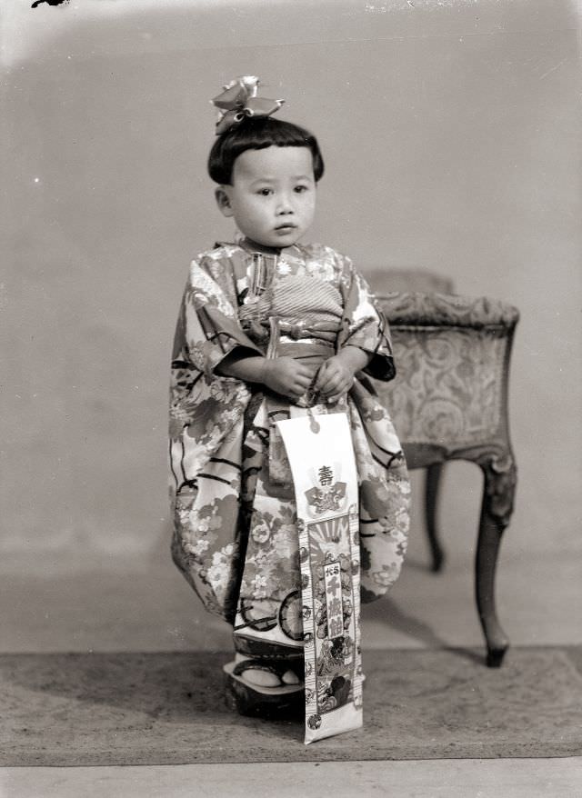 A Japanese child in a kimono with the traditional Shichi-Go-San candy, a hair bow and sandals