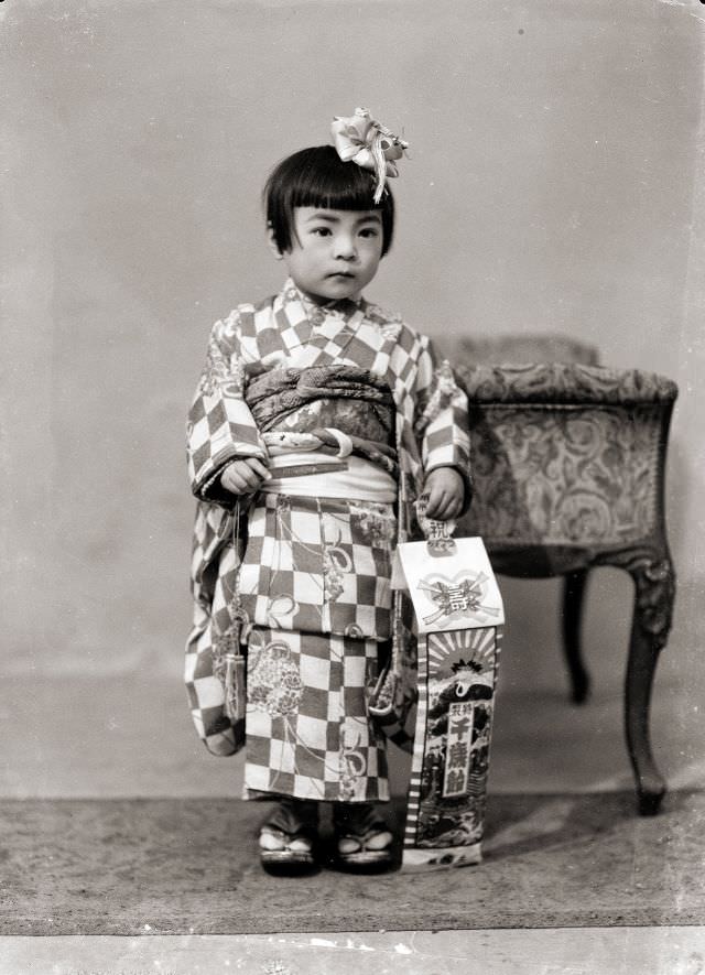 A Japanese girl in a checkered kimono and hair bow with traditional Shichi-Go-San candy