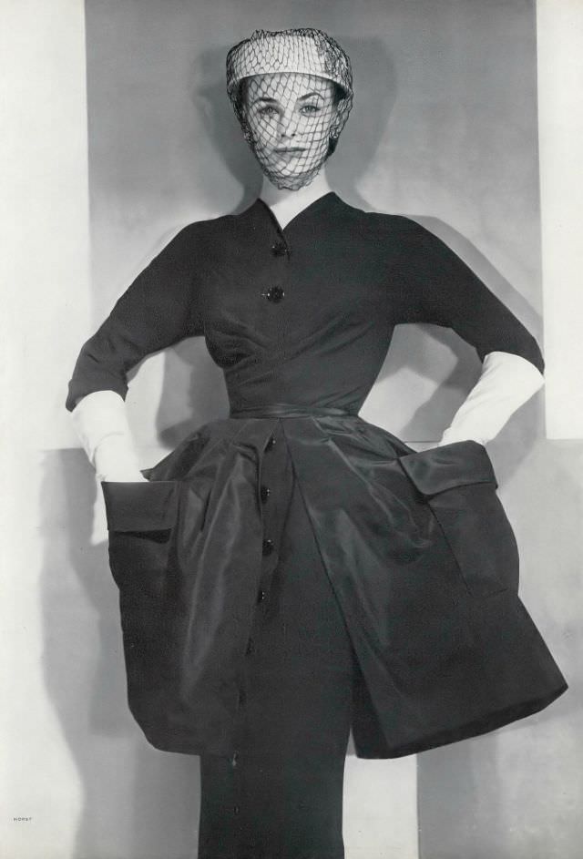 Lillian Marcuson in black rayon sheath with an overskirt of black rayon taffeta by Hannah Troy, stark white panne velvet hat by Lilly Daché, Vogue, November 1, 1950