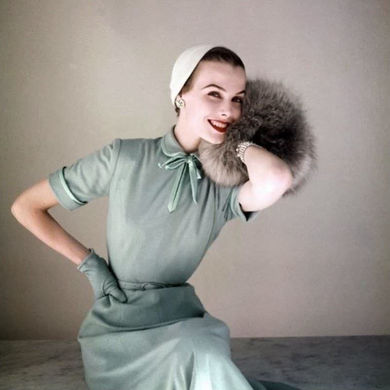 Lillian Marcuson in Heller baby blue worsted jersey dress with satin bow at neck by Richard Cole, little felt hat by Amy and Norwegian blue fox muff by Annis Furs, 1952