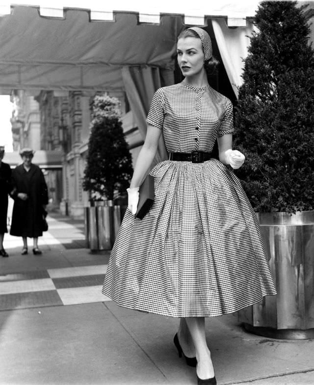 Lillian Marcuson with the outside layers of hat and dress removed, the wide-skirted checked taffeta by Traina-Norell and matching cap by Emme can be worn to parties, 1955
