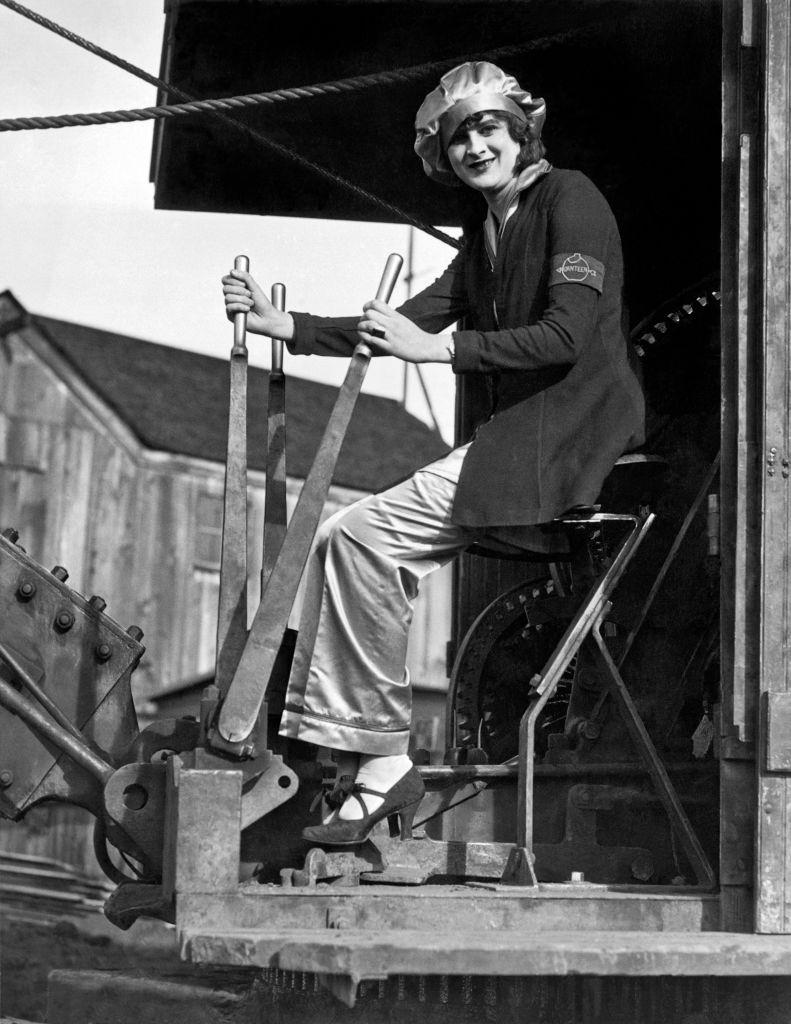 A smiling woman at the controls of a steam shovel, Oakland, 1930.